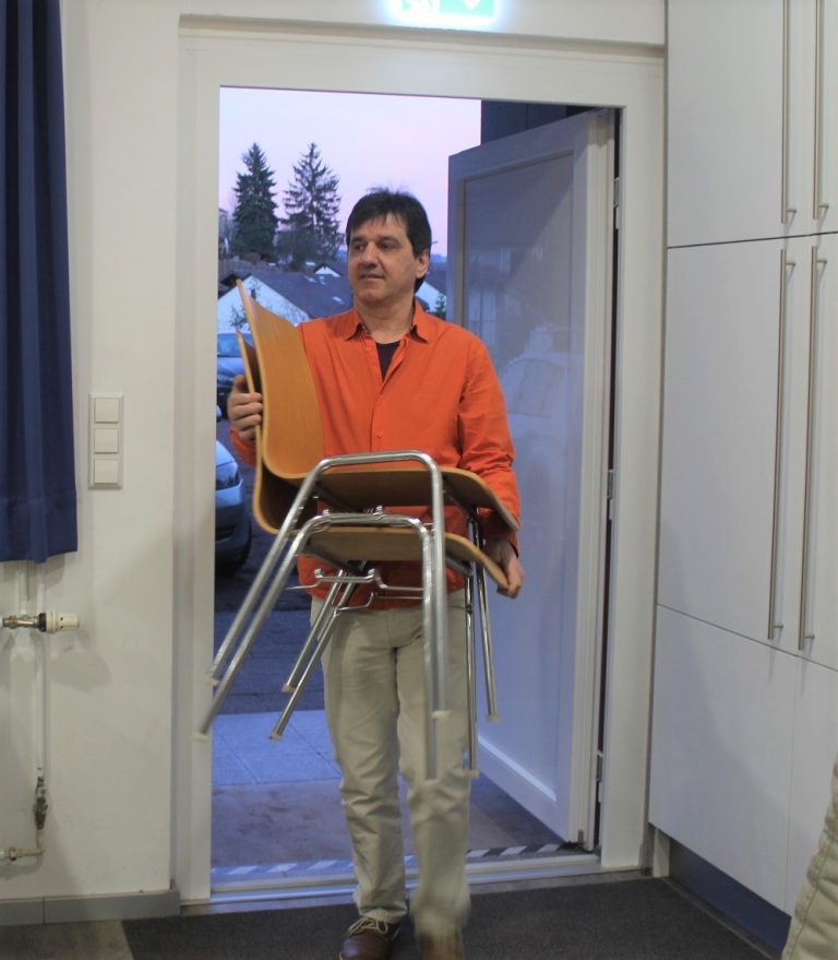 Sakis trägt Stühle in den Seminarraum